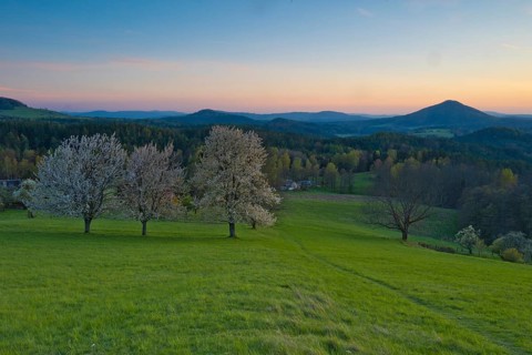 View of Ružák, Rosenberg, across the spring-like Bohemian Switzerland with blooming fruit trees,