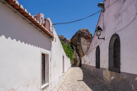 Narrow alley between white walls and cobblestones in sunshine, Serpa, Beja, Portugal