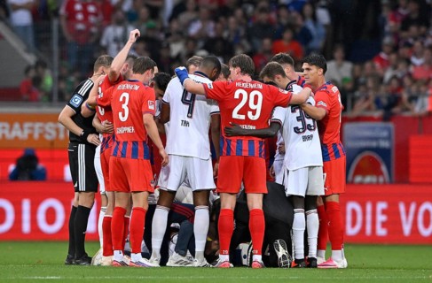 Jamal Musiala of FC Bayern Munich (FCB) (10) collapses on the pitch, teammates rush to his aid and