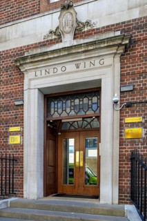 The Lindo Wing entrance at St Mary's Hospital shows the stone pediment, leaded overlight and worn