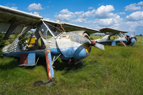 Two weathered, rusted aircraft are next to each other on a green field, PZL-104 Wilga multi-purpose