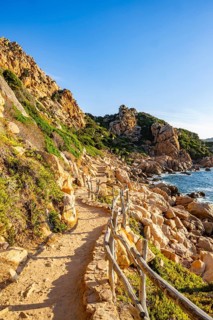 A little trail passing the rocks at the coastline with blue water at Costa Paradiso on a sunny day