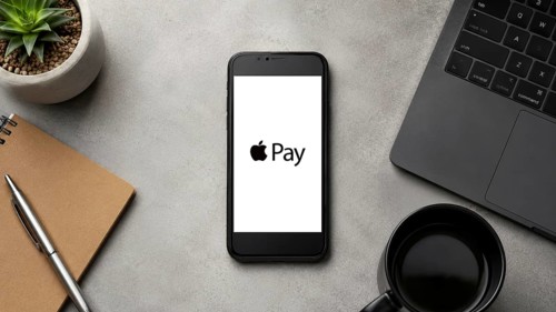 In this photo illustration, a smartphone displays the Apple Pay app logo on a minimalist office