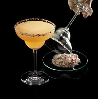 Orange-colored cocktail on a black background, salt rim as a garnish, glass with salt rim is