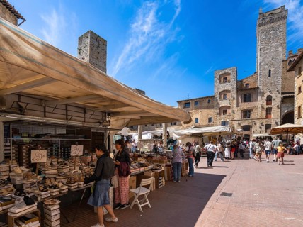 Tourists around the market square with old fountain and other sights in San Gimignano, Tuscany,