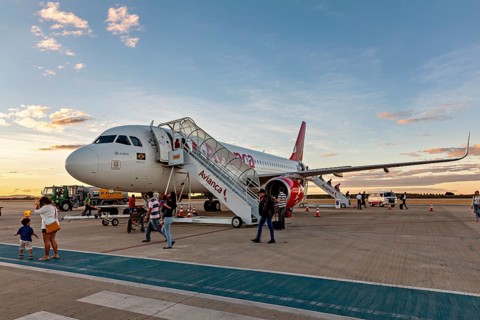 An Avianca plane is parked at the airport with stairs and passengers as the sun sets, airplanes on