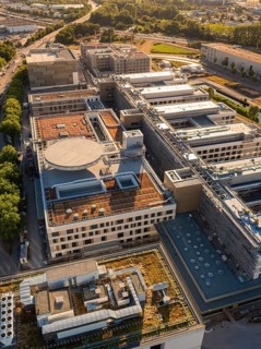 Complex building structures from an aerial perspective, surrounded by trees and roads, construction