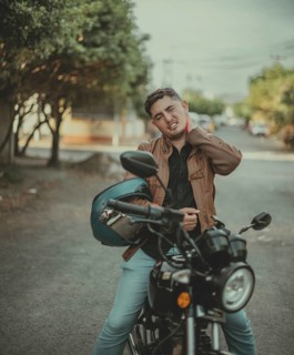 Young motorcyclist suffering from neck pain on the road. Male motorcyclist with stress and neck