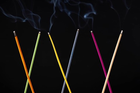 Smoking colorful incense sticks against black background