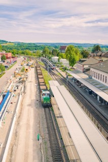 Station in a green landscape with trains and adjacent buildings, construction site by Leonhard