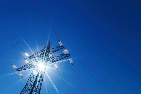 The sun shines through a tower of a high-voltage line for electricity. Sonnenenergie, Austria