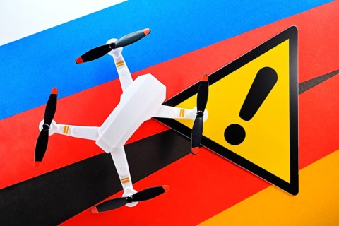Drone on flag of Russia and Germany with warning sign, symbolic photo of Russian drone strikes and