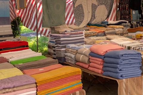 Neatly folded textiles and towels arranged on tables in a market stall