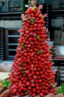 Glossy strawberries are stacked into a tall pyramid and trimmed with mint leaves and miniature