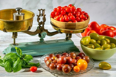 Different types of tomatoes and basil on and around old scales, colorful and attractively presented