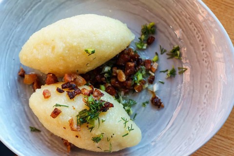 Lithuanian national dish zeppelins or Cepelinai or didzkukuliai with fried bacon and herbs, top