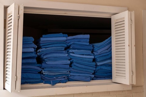 A window displays neatly stacked blue towels in a hotel setting in Turkiye. The towels are folded