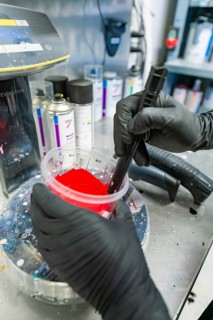 Preparation of red paint in the workshop by a person with black gloves, painter, Calw, Germany