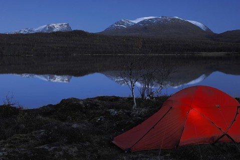 Bivouac, tent by a lake in Abisko National Park with Lapporten reflected in the water, Norrbotten,