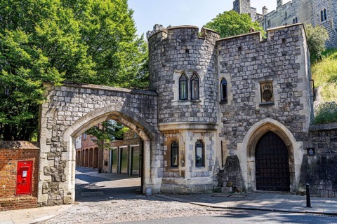 A small castellated gatehouse with a corner turret and pointed archways opens onto Chapter Mews, a