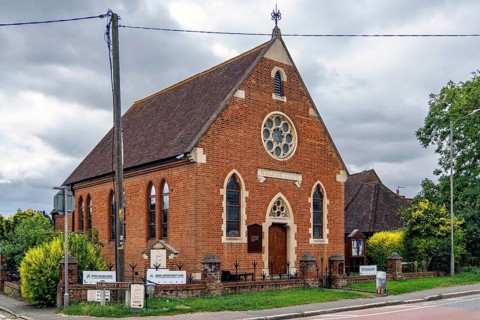 Red brick former Wesleyan Methodist chapel of 1877 with rose window and gothic arches, now