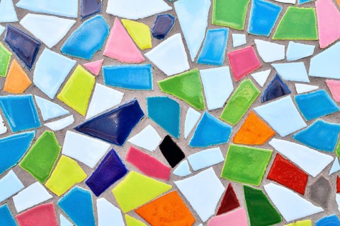 Close up of wall made of irregular colorful mosaic stones, uneven textured decorative surface with