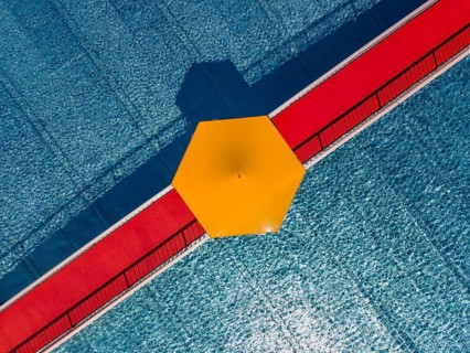 On a red bridge spanning a swimming pool at an open-air lido in Frankfurt, there is a yellow