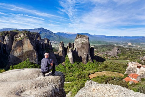 Hiker photographs views of hermitages between high rocks, monasteries on sandstone formations,