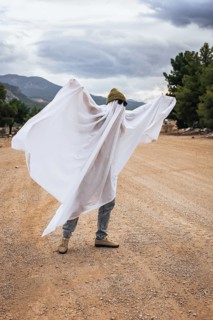 Person dressed as a ghost in a homemade Halloween costume outdoors. Funny seasonal celebration,