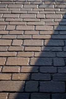 A broad building shadow cuts across rectangular stone paving in strong sunlight, Saint-Tropez, Var,