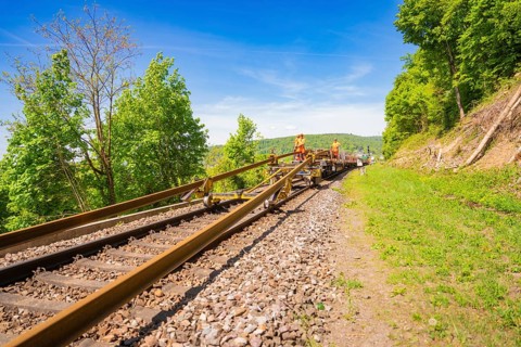 Technicians work on railroad tracks in a green environment under blue skies, Leonhard Weiss