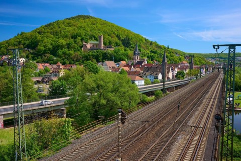 A town with railroad tracks near a hill, overlooked by historic buildings, Gemünden am Main,