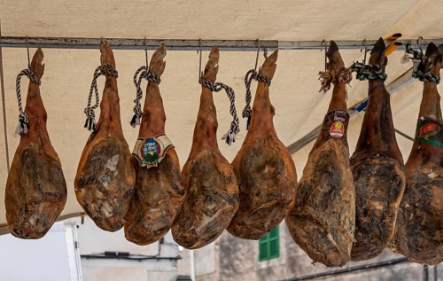 Sales stand with whole pork ham, farmers market, weekly market market, Sineu, Majorca, Spain