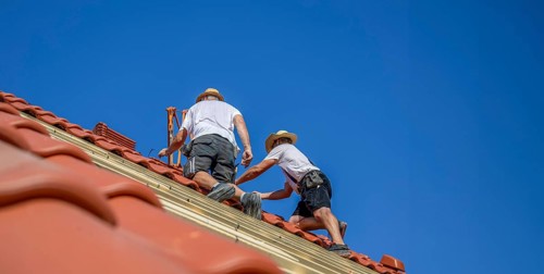 Roofers covering a tiled roof