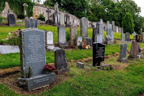 Rows of weathered headstones fill the cemetery beside Rosslyn Chapel in Roslin, Midlothian,