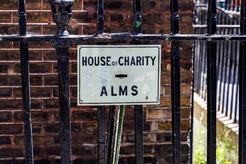 A House of Charity sign marks a victorian penny chute set into the railings that once let passers