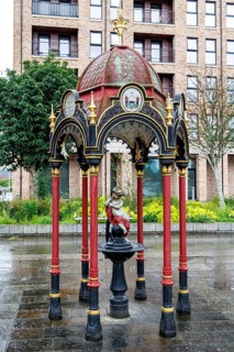 Ornate red and gold cast iron Victorian drinking fountain dedicated to Dr John Aitken, standing at