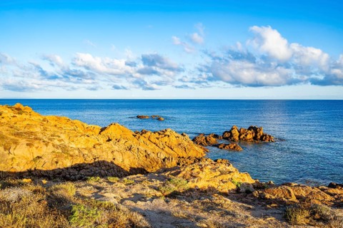 Landscape of the coastline with blue water at Marinedda Coast at sunset, Sardinia, Italy