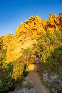 A little trail going through the bushes at the coastline at Costa Paradiso on a sunny day at