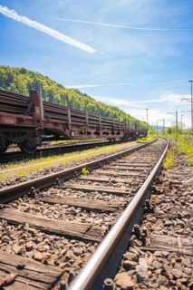 Railway tracks lead through a green landscape under a bright blue sky, Leonhard Weiss construction