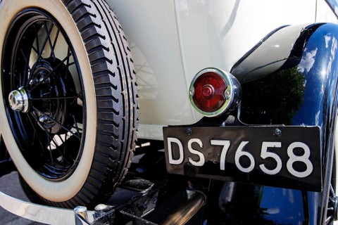 Whitewall wire wheel and black registration plate on a cream vintage tourer