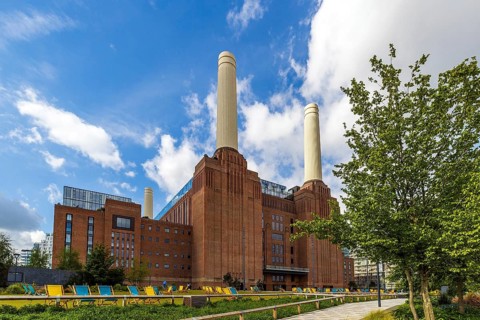 Fresh spring leaves frame the twin Art Deco chimneys of Battersea Power Station, London, England,