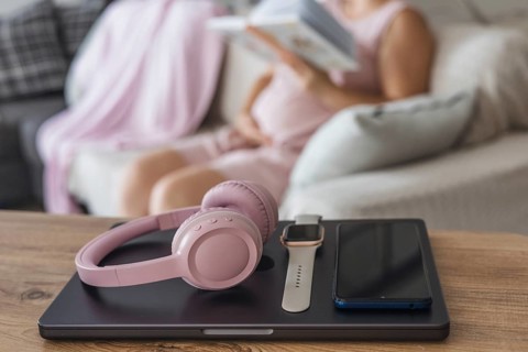 Digital detox during a cozy afternoon at home with headphones and a book in hand. Pregnant woman