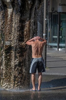 Young man refreshes at a well in the summer heat, Nuremberg, Middle Franconia, Bavaria, Germany