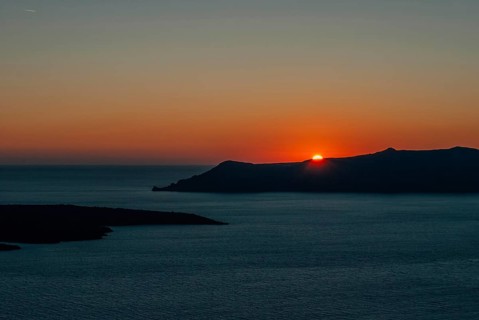The sun at sunset almost disappeared behind the island, Santorini, Greece, A tranquil sunset over