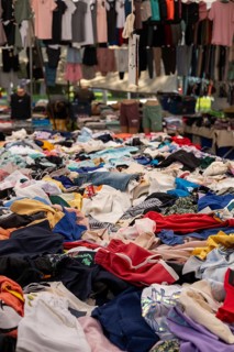Mixed clothing items heaped in a vibrant outdoor market setting