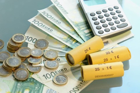 A pocket calculator and euro coins on the table, studio photo, Lower Saxony, Federal Republic of