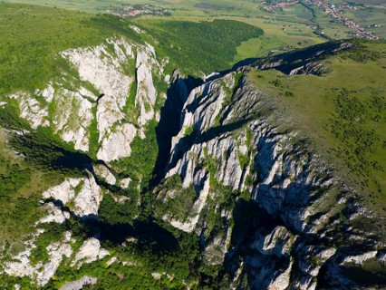 Bird's eye view of dramatic rocks and vast green valleys extending to the horizon, aerial view,