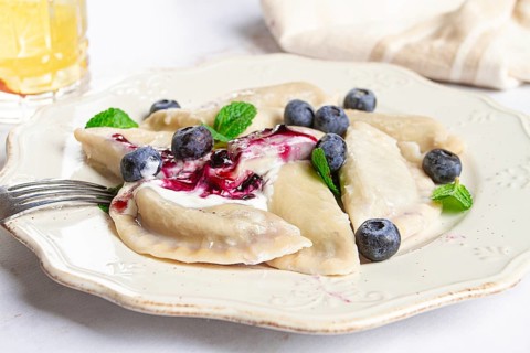 Handmade dumplings filled with sweet ingredients, arranged beautifully on a white plate, topped