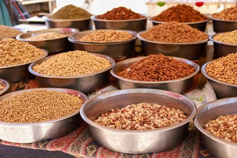 Various nuts and seeds presented in metal bowls at a market stall
